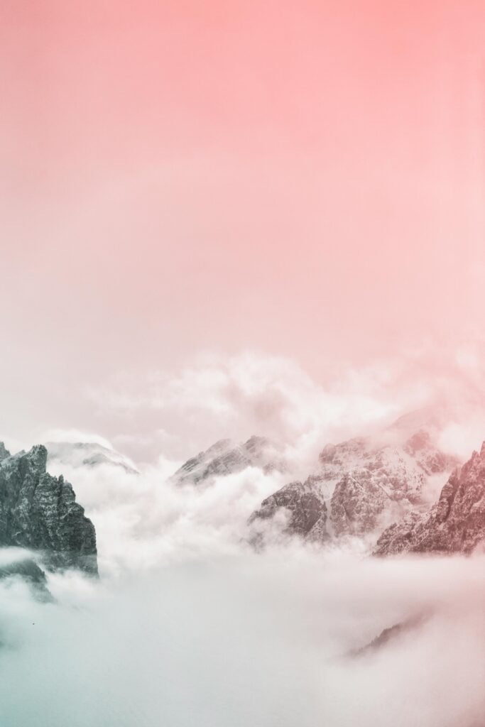 Breathtaking view of rocky mountains enveloped in foggy clouds during a winter dawn.